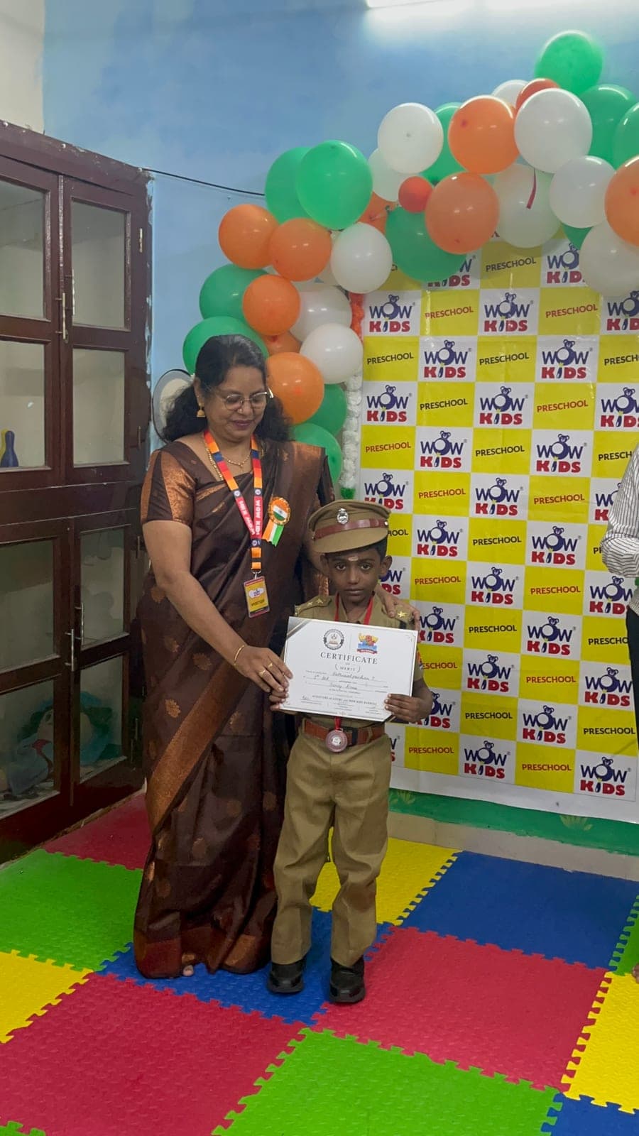 Teacher presenting a certificate of appreciation to a preschooler dressed as a police officer